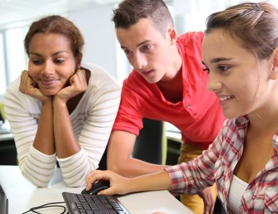 Drei Studierende vor einem PC