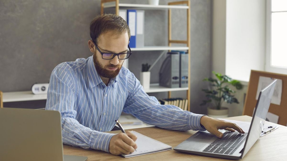 enlarge the image: Man at a desk working on two laptops