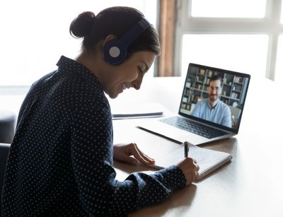 Frau sitzt vor ihrem Laptop und tätigt eine Videokonferenz