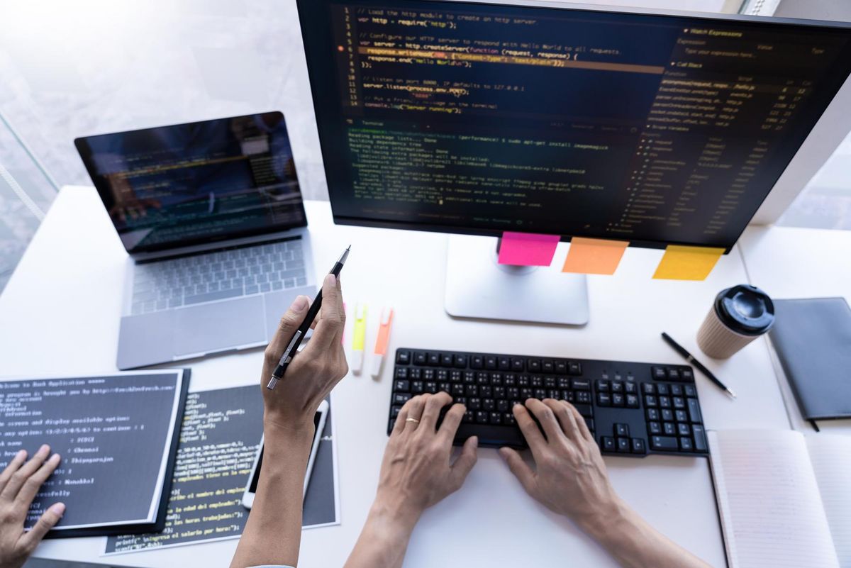 enlarge the image: Two people at a desk looking at computer displays