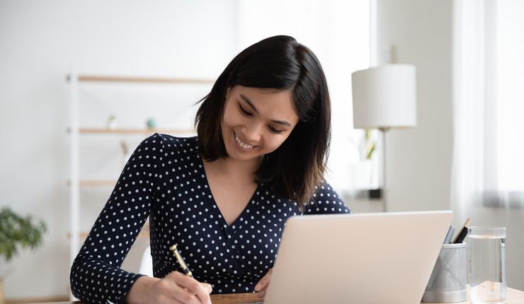 Eine junge Frau am Schreibtisch, vor ihr ein Laptop