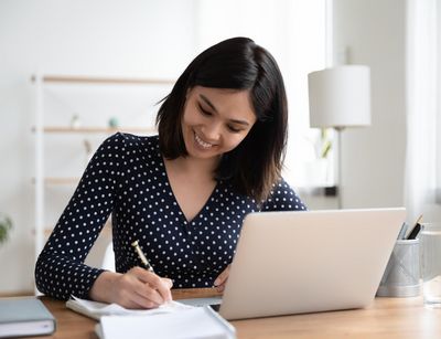 Eine junge Frau am Schreibtisch, vor ihr ein Laptop