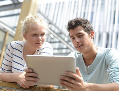 Eine junge Frau und ein junger Mann schauen auf ein Tablet