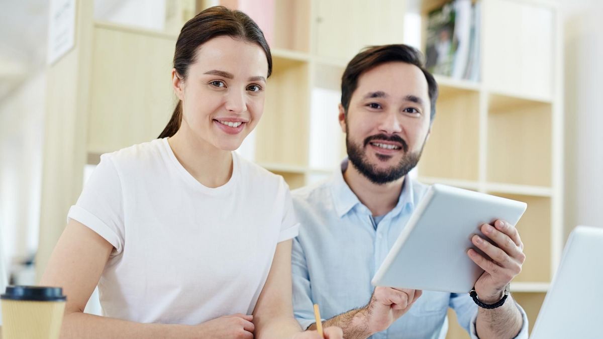 enlarge the image: Woman and a man sitting next to each other on a desk