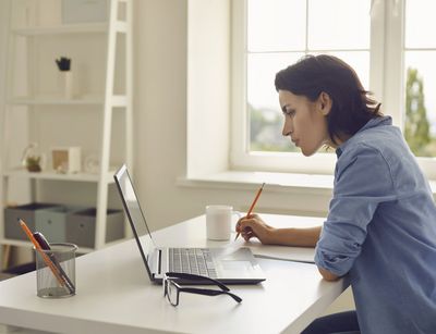 Frau an einem Schreibtisch mit Laptop und Schreibmaterial