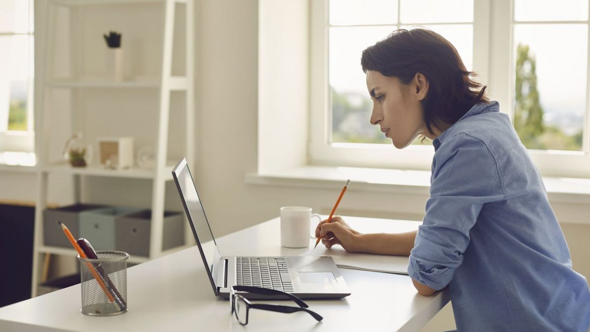 Frau an einem Schreibtisch mit Laptop und Schreibmaterial