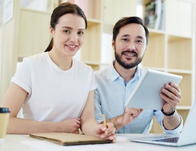 Eine Frau und ein Mann nebeneinander an einem Schreibtisch