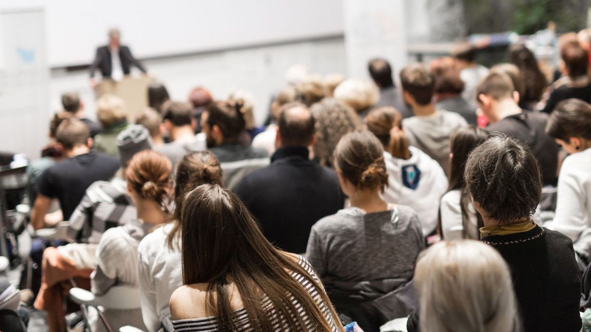 zur Vergrößerungsansicht des Bildes: Menschen in einem Hörsaal von hinten fotografiert