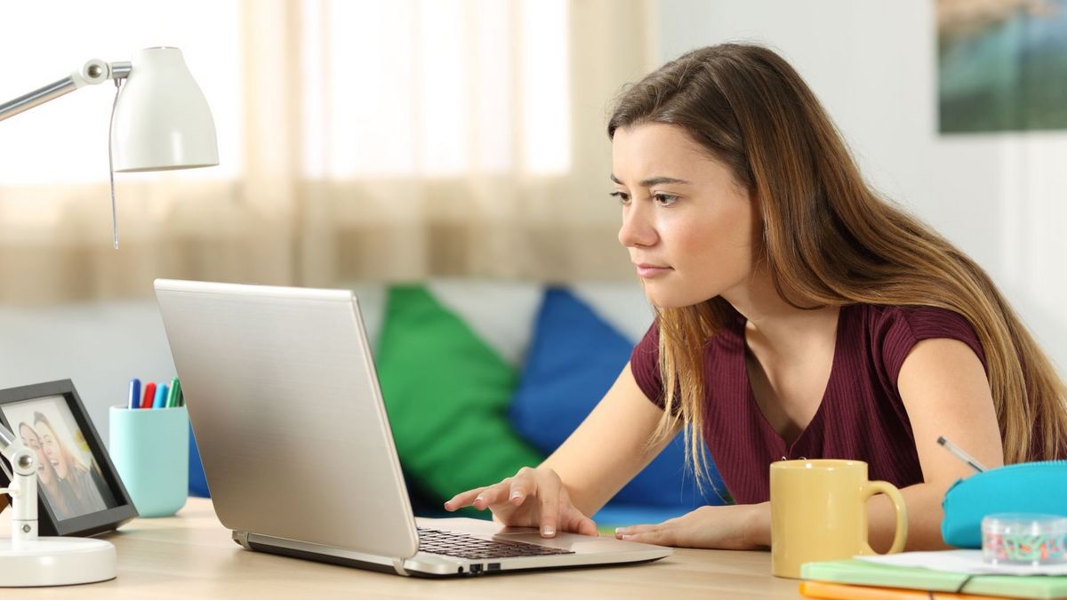 Eine junger Frau guckt auf einen Laptop