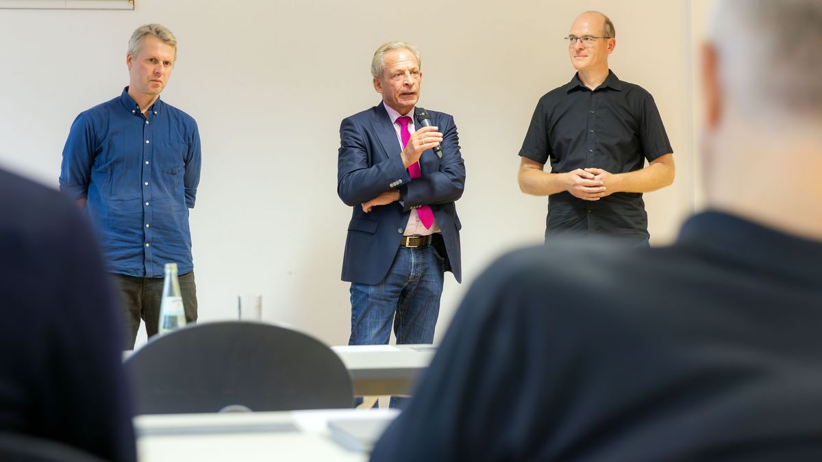 zur Vergrößerungsansicht des Bildes: Drei Männer stehen nebeneinander und diskutieren über die Zukunft der Lehre. 