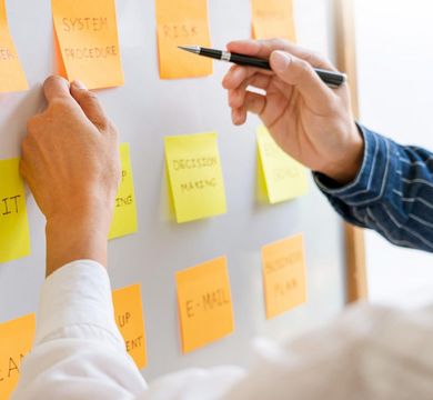 Foto: Colourbox Zwei Menschen zeigen auf Post-it-Zettel an einem Whiteboard